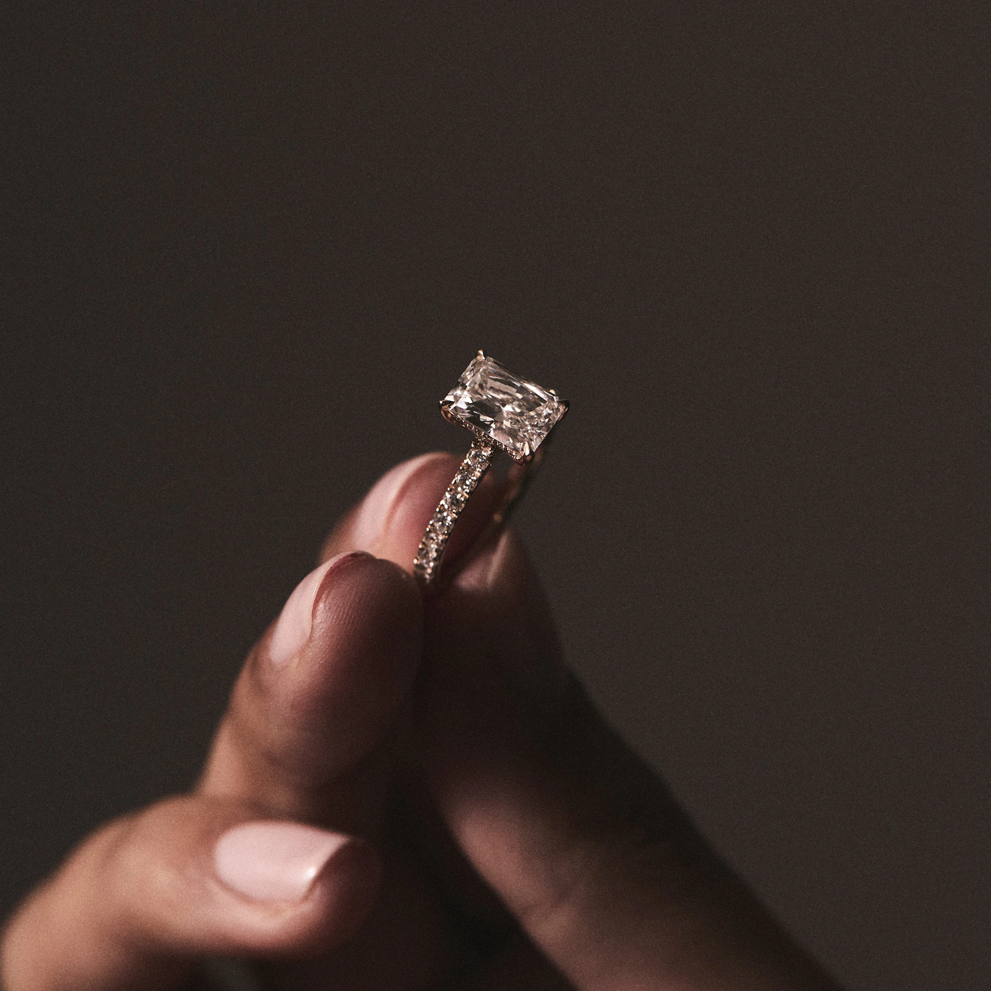 woman holding emerald cut diamond ring