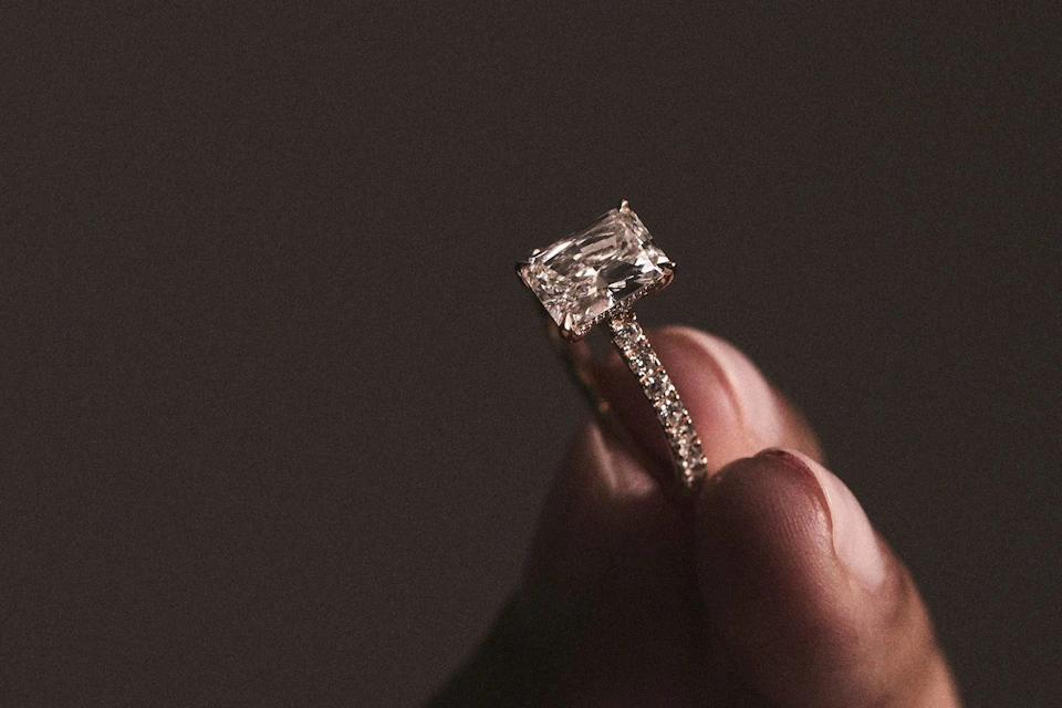 woman holding emerald cut diamond ring