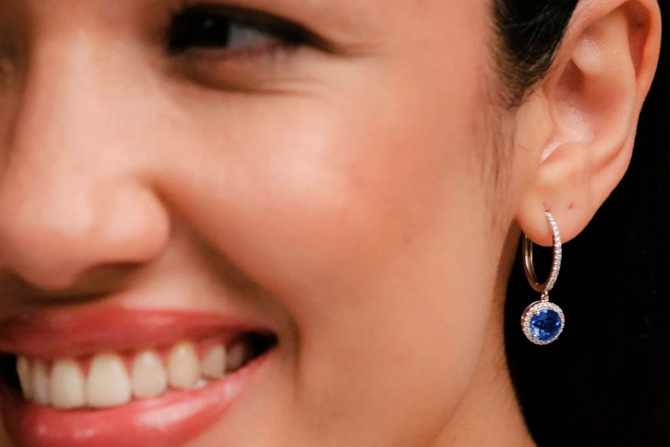 woman wearing blue sapphire diamond halo drop earrings