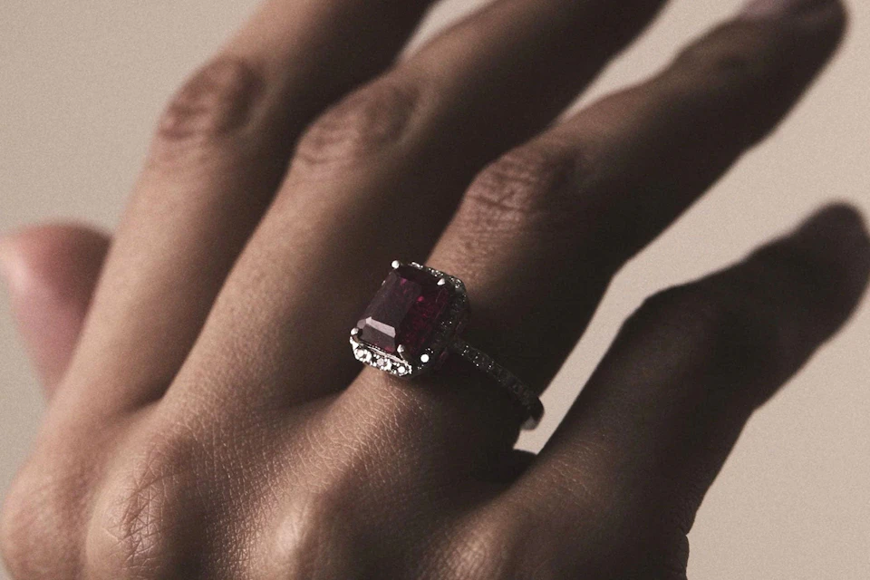 Ruby and diamond halo ring shown in a hand
