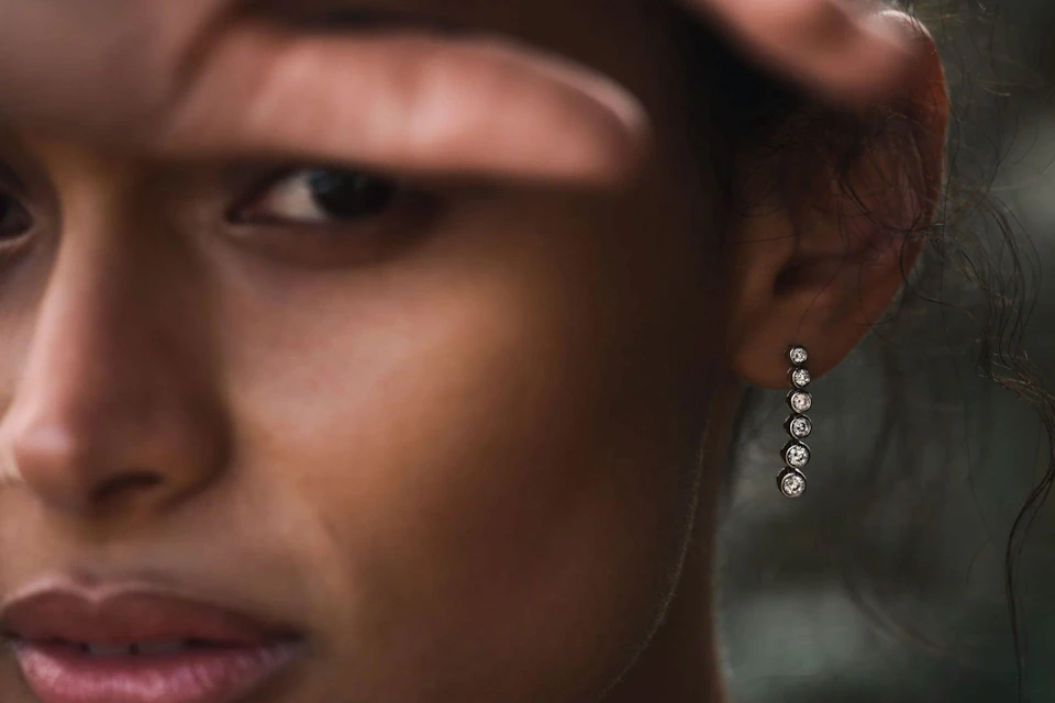 woman wearing rubover setting diamond earrings