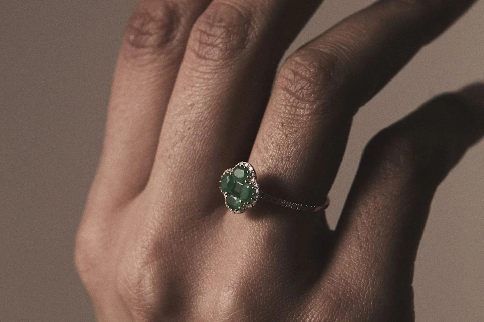 hand with an emerald clover yellow gold ring